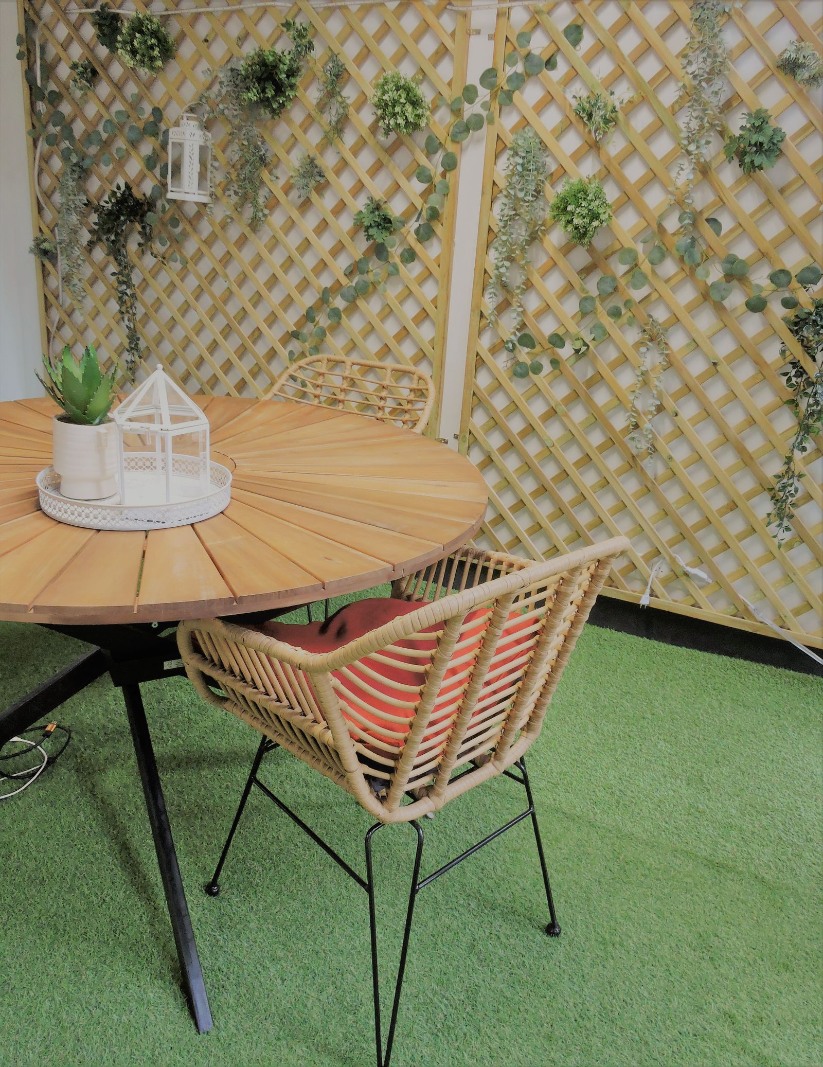 Artificial turf patio seating area with a rattan chair and wooden table