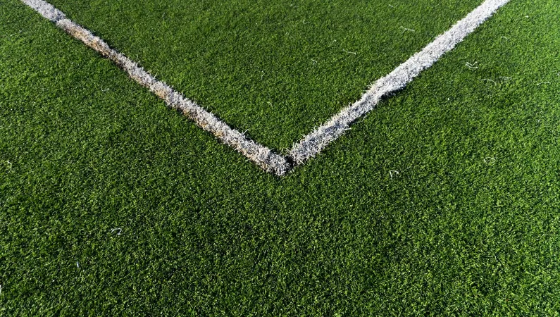 Worn artificial turf sports field under harsh direct sun